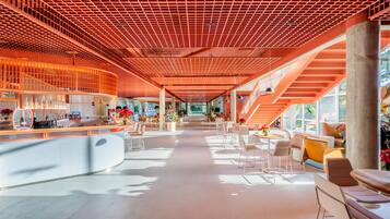 A spacious interior with a modern bar area, seating arrangements, and a staircase leading to upper levels.