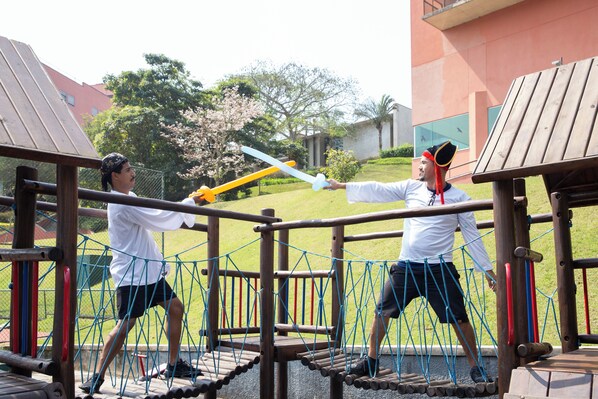 A playground with wooden climbing structures and netted bridges. - Almenat Embu das Artes, Tapestry Collection by Hilton (Embu das Artes)