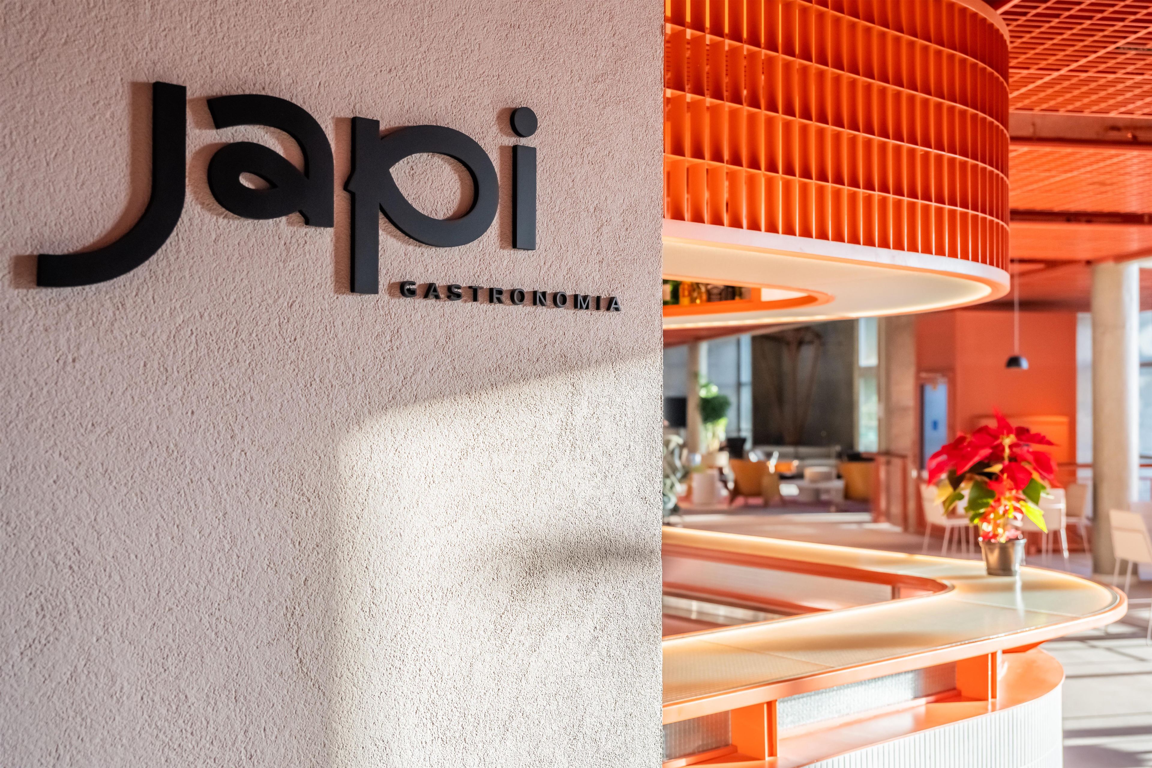 A modern interior with a sign reading 'Japi Gastronomia' on a textured wall.