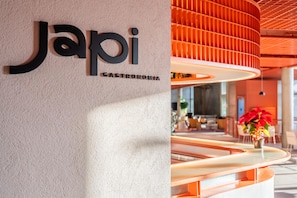 Um interior moderno com uma placa que diz 'Japi Gastronomia' em uma parede texturizada.