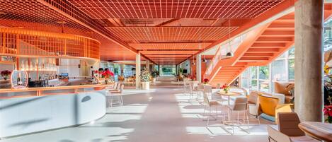 A spacious lobby with a curved reception desk, seating areas, and a staircase.