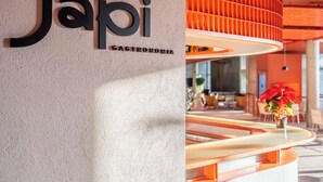 A modern interior with a sign reading "Japi Gastronomia" and a curved seating area with a warm, orange-lit ceiling. - Almenat Embu das Artes, Tapestry Collection by Hilton (Embu das Artes)