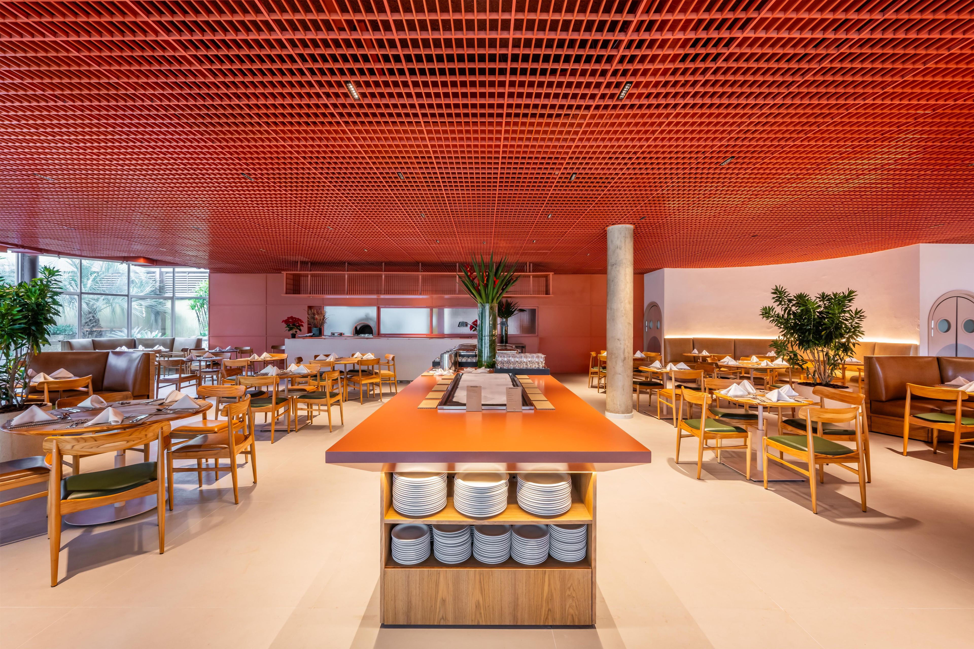 A modern interior with a central bar area, multiple seating arrangements, and a red ceiling.