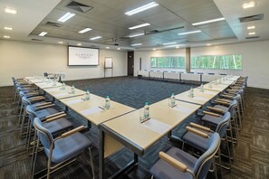 A conference room with a long table, chairs, a projector screen, and a presentation screen. - Almenat Embu das Artes, Tapestry Collection by Hilton (Embu das Artes)