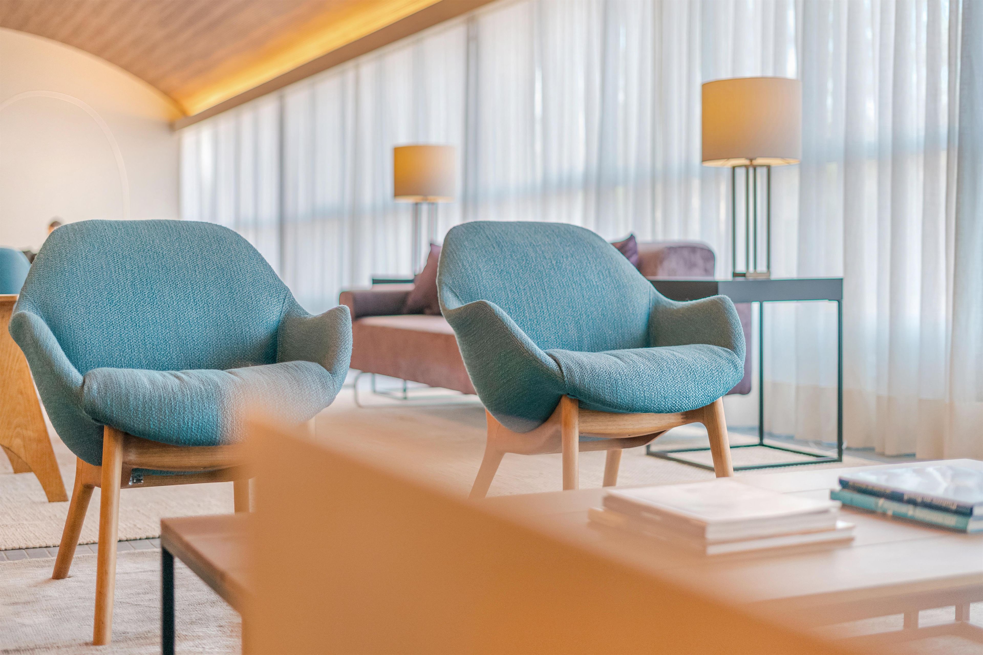 Un salon moderne comprenant deux fauteuils, un canapé, une table basse et deux lampadaires.