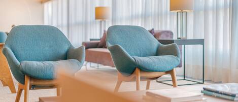 Uma sala de estar moderna com duas poltronas, um sofá, uma mesa de centro e duas luminárias de chão.