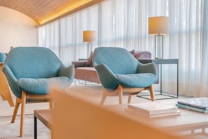 Uma sala de estar moderna com duas poltronas, um sofá, uma mesa de centro e duas luminárias de chão.