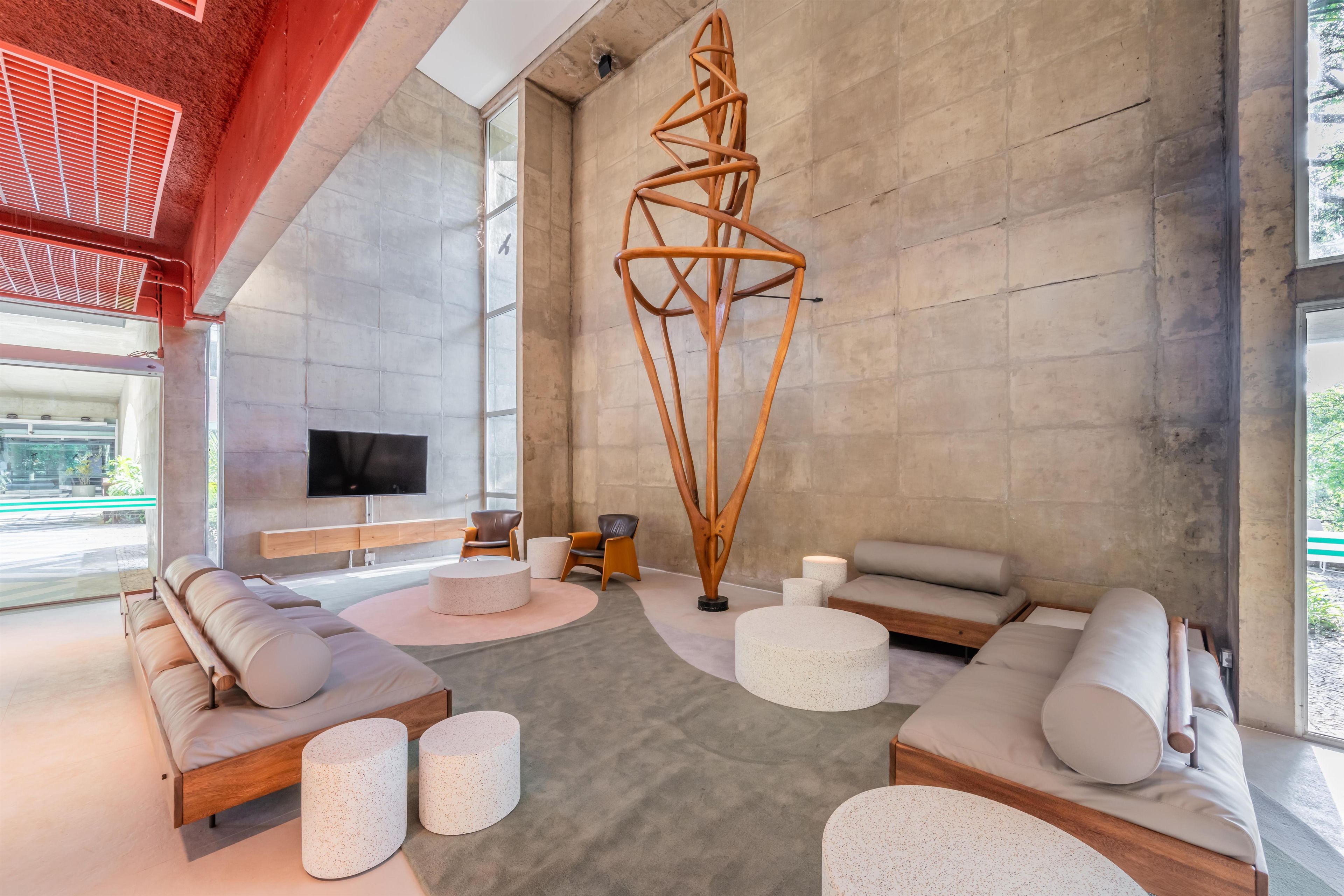 Una sala de estar moderna con un televisor grande, sofás y una escultura de madera original.
