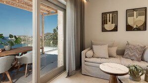 A modern living room with a sofa, a small round table, and a view of the sea. - Sea View Villa w/ Private Pool & BBQ (Heraklion, Crete)