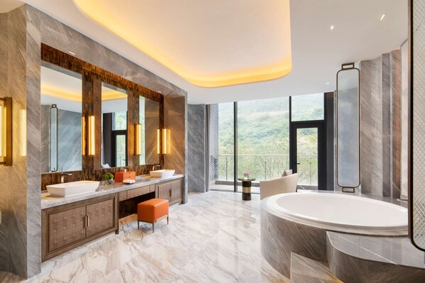 Un baño moderno con un espejo grande, dos lavamanos, una bañera y vistas al exterior.