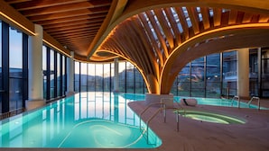 A modern indoor swimming pool with a curved wooden ceiling and large windows offering views of the surrounding landscape. - Radisson Collection Resort, Nanjing (Nanjing)