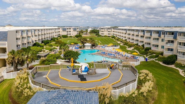 Un resort con piscina central, varios balcones y céspedes bien cuidados.