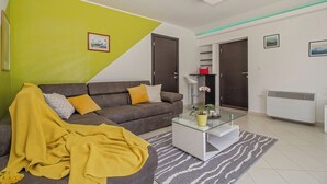 Ein Wohnzimmer mit einer Couch, einem Glastisch und einer gelben Decke.