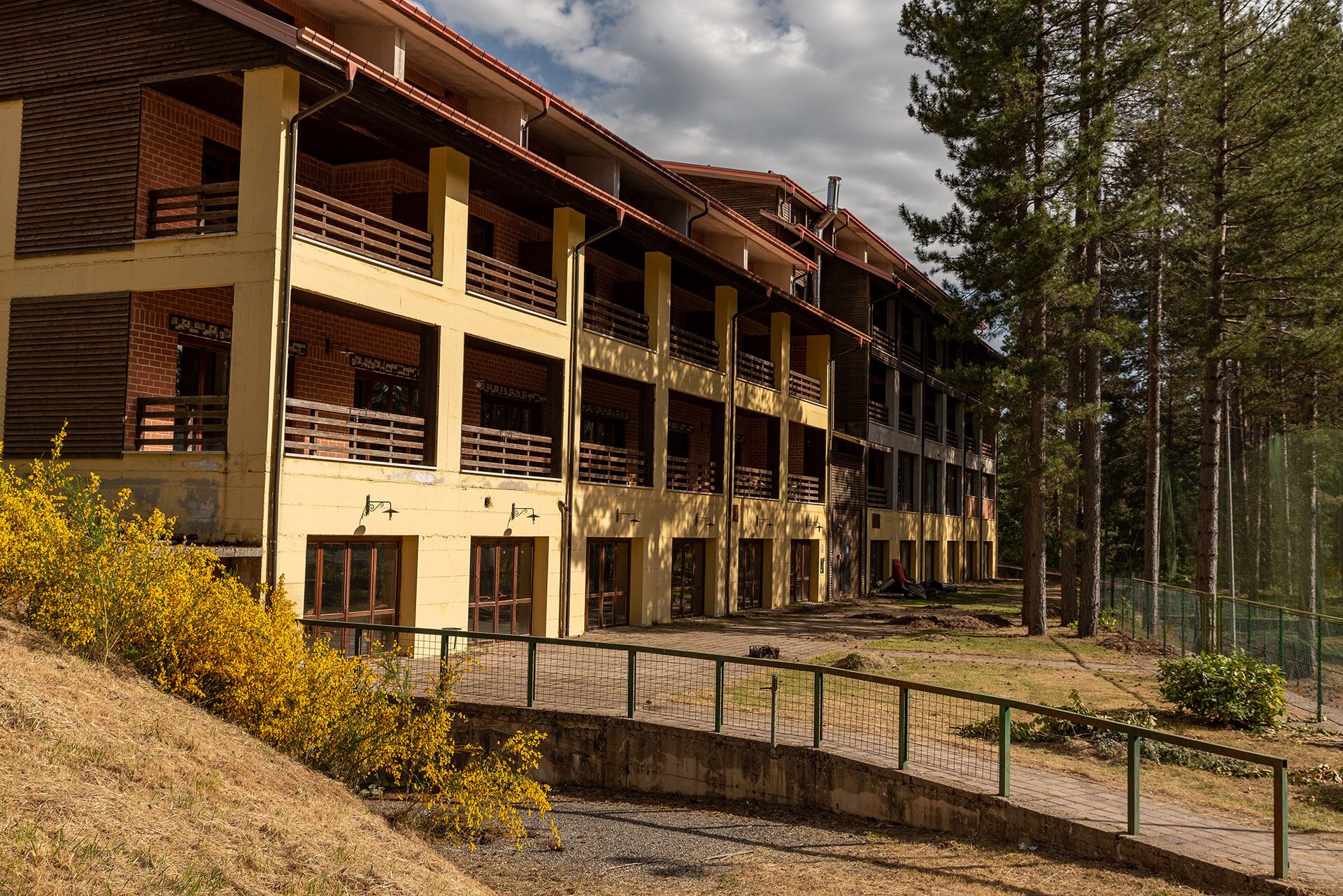 Ein mehrgeschossiges Gebäude mit Balkonen, einer Ziegel-Fassade und einer umliegenden Waldlandschaft.