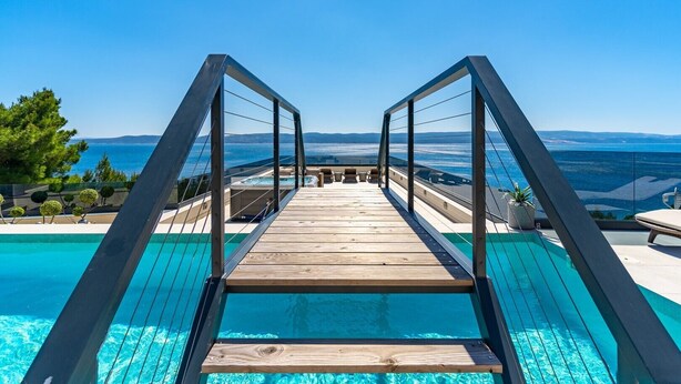 A wooden deck leading to a pool with a clear view of the sea and distant mountains. - Seaview Villa Blue Lagoon with private heated pool, 2 jacuzzies, sauna, media room, 6 bedrooms, beach 70m (Pisak)