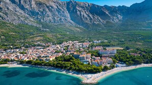 A coastal town with buildings, a beach, and mountains in the background. - Seaview Villa Blue Lagoon with private heated pool, 2 jacuzzies, sauna, media room, 6 bedrooms, beach 70m (Pisak)