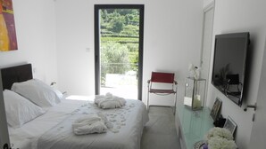 A bedroom with a bed, a desk with a mirror, and a view of greenery outside. - Villa Exceptionnelle , Avec vue Panoramique (Venasque)