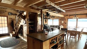 Une cuisine spacieuse avec des poutres apparentes, un îlot central et un coin repas comprenant une grande table et des chaises.