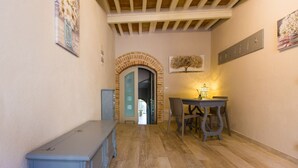 A hallway with a wooden floor, a blue cabinet, a table with chairs, and a lit lamp. - San Gimignano Town Garden - 4 pax (San Gimignano)