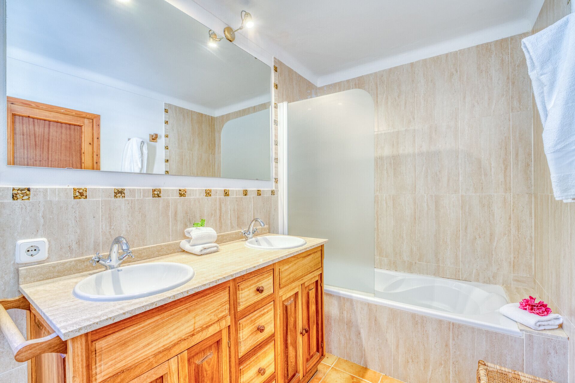 A modern bathroom with two sinks, a large mirror, and a bathtub.