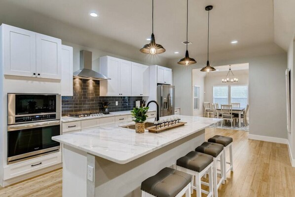 A modern kitchen with white cabinetry, stainless steel appliances, and a central island with bar stools.