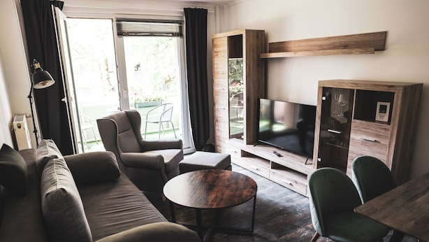 Ein Wohnzimmer mit Sofa, Sessel, Couchtisch und Fernsehmöbel.