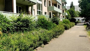 Ein Wohngebäude mit mehreren Balkonen und einem gepflasterten Weg.