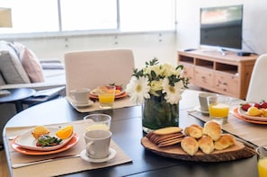 A breakfast setting with plates of food, glasses of orange juice, and a vase of flowers on a table.