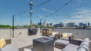 Eine Dachterrasse mit Sitzgelegenheiten im Freien, einem Grill und Blick auf die Stadtlandschaft.