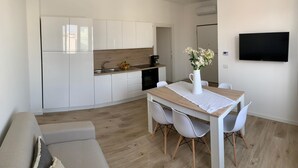 Una cocina moderna con armarios blancos, encimera de madera y una zona de comedor con mesa y sillas.