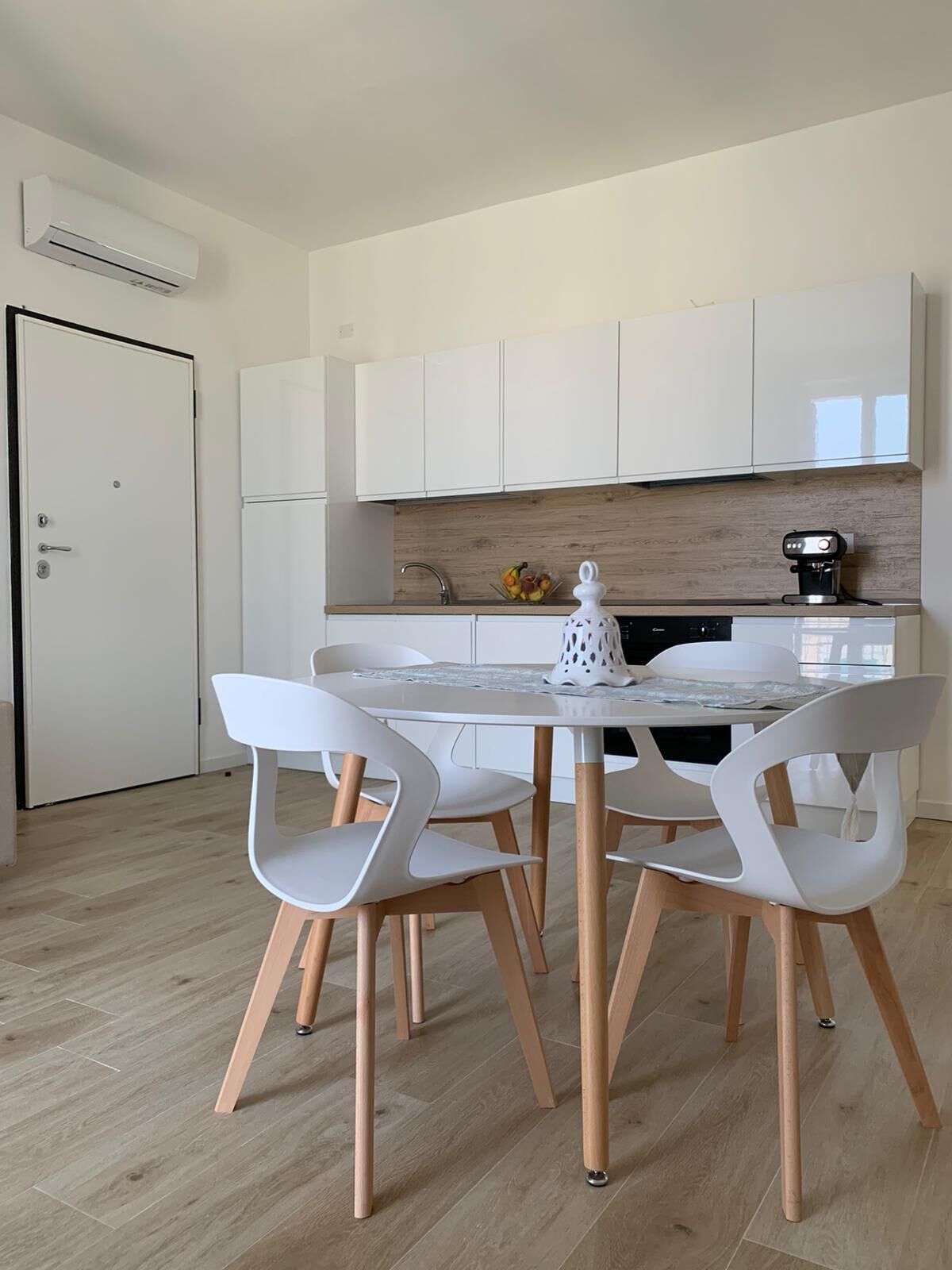 Une cuisine moderne avec des meubles blancs, un plan de travail en bois et une machine à café.