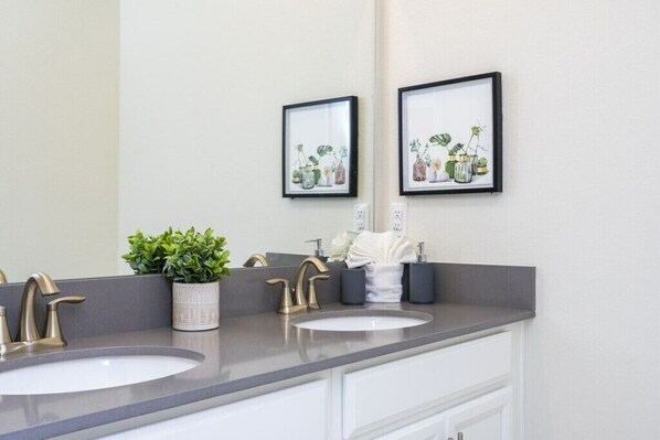 A bathroom with two sinks, a mirror, and framed artwork above the mirrors.