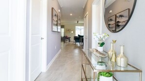 A hallway with a glass console table, decorative vases, and a mirror. - Amazing Villa 5BR - Private Pool & Themed Rooms - 5 miles Disney! (Kissimmee)