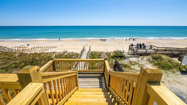 A wooden staircase leading to a beach with a clear view of the ocean and a wooden boardwalk with people walking. - Ocean front gem offering 6BR/5BA with direct beach access! (North Topsail Beach)