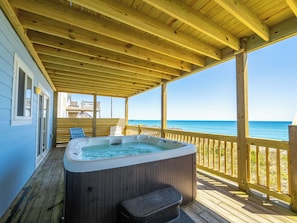 Eine Holzterrasse mit Whirlpool, Holzgeländern und Blick auf den Ozean.