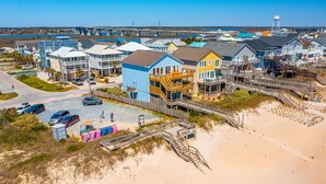 A coastal residential area with colorful houses, a beach, and a bridge in the background. - Ocean front gem offering 6BR/5BA with direct beach access! (North Topsail Beach)