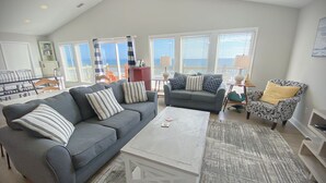 A living room with a grey sofa, a patterned armchair, and a white coffee table. - Ocean front gem offering 6BR/5BA with direct beach access! (North Topsail Beach)