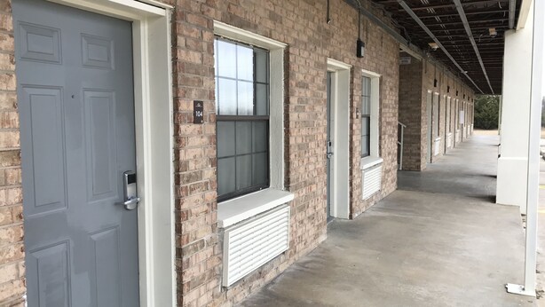 A row of rooms with brick walls, white trim, and large windows.