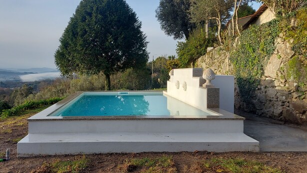 A rectangular swimming pool with a clear blue water surface, surrounded by a white concrete deck. - Casas da Tapada - Casa das Cortes (Guimarães)