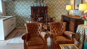 A living room with two brown leather armchairs, a wooden cabinet, and a dining table. - Casas da Tapada - Casa das Cortes (Guimarães)