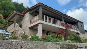 A two-story house with a balcony, stone walls, and a car parked in front. - Casas da Tapada - Casa das Cortes (Guimarães)