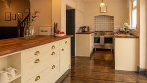 Una cocina con encimeras de madera, armarios blancos, horno empotrado y salpicadero de azulejos.