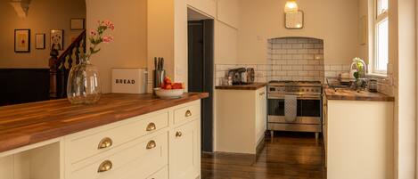 A kitchen with wooden countertops, white cabinets, a built-in oven, and a tiled backsplash.