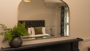 Un dormitorio con cama, planta en maceta, espejo y mesita de noche.