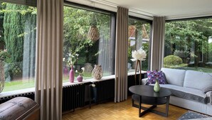 Un salón moderno con un ventanal grande, un sofá, una mesita y adornos.