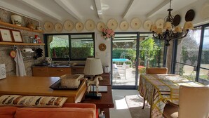 Cuina moderna amb microones, forn i rentapesos. Zona de menjador amb taula i caires, i un sofà. L'habitació té grans finestres amb vista al jardí.