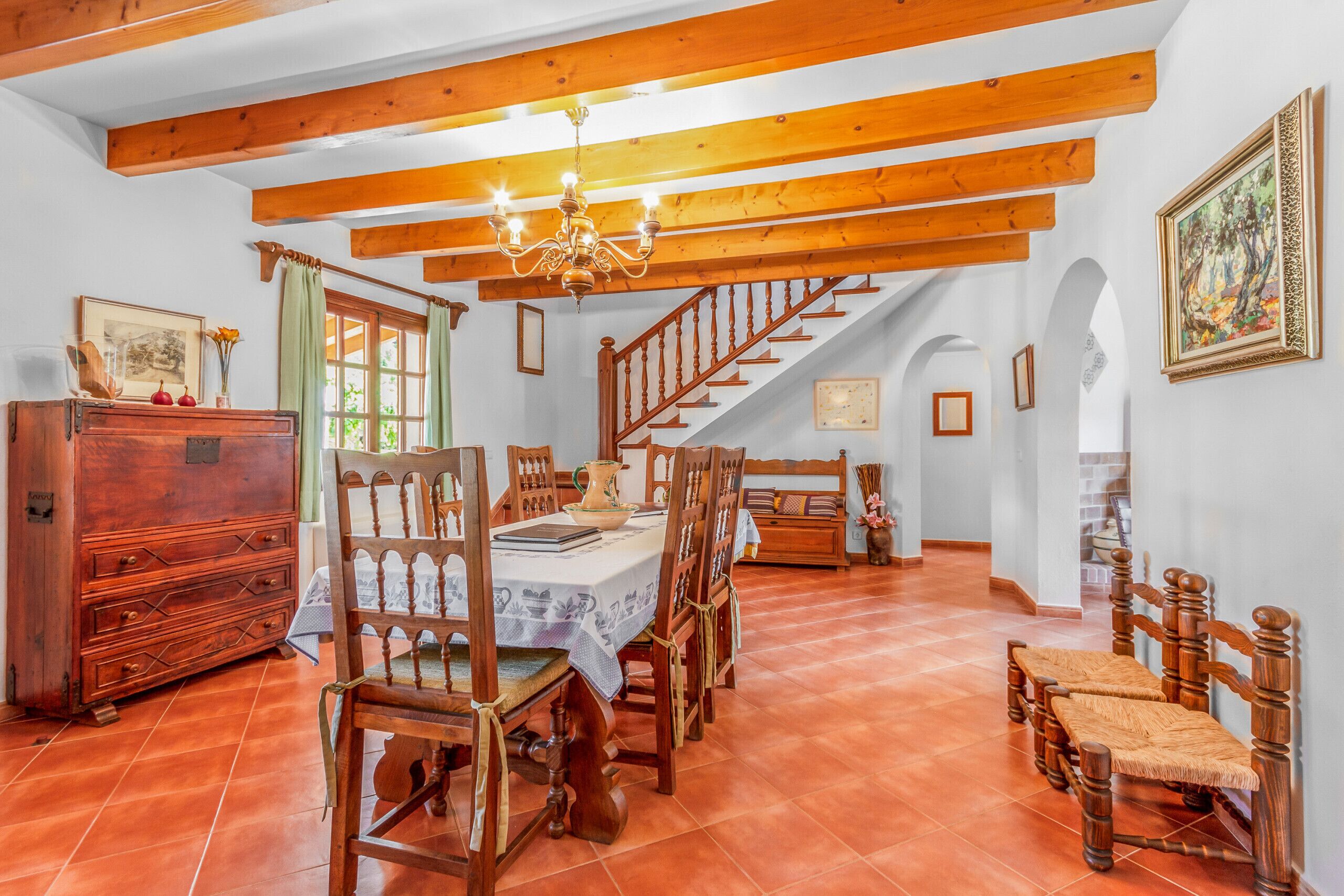 A dining area with wooden furniture, a chandelier, and a staircase leading to another level.