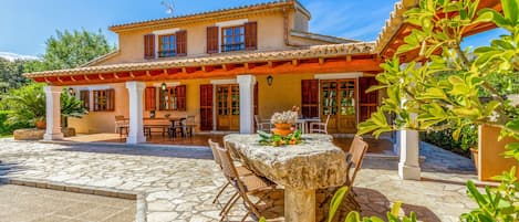 A two-story house with a patio area, a dining table, and chairs.