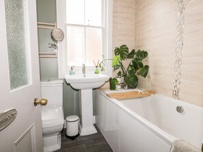 A bathroom with a white sink, toilet, and bathtub. There is a window above the sink and a mirror on the wall. - 39 West Street (Scarborough)