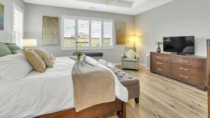 Een slaapkamer met een groot bed, een televisie, een stoel en een dressoir.